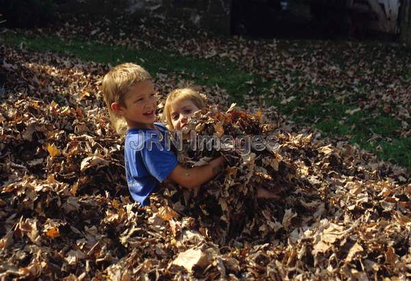 Boy and girl playing in fallen leaves